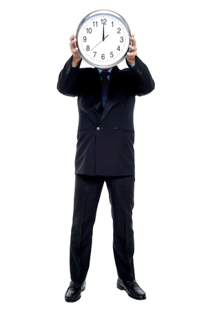 Executive holding up wall clock in front of his face. Clock striking 12.の写真素材