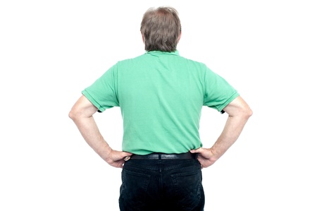 Back pose of elderly guy with hands on his waist. Facing opposite side.