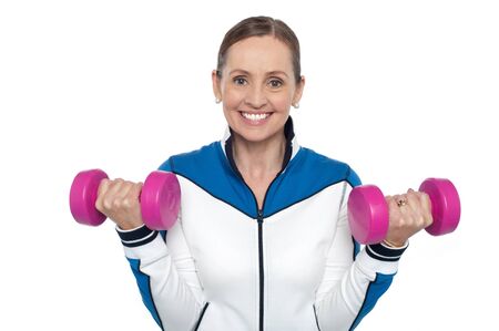 Happy woman carrying dumbbells in both hands isolated against white background.
