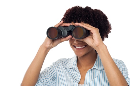 Casual young woman watching closely through binoculars.の写真素材