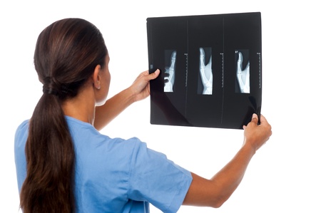 Young female doctor analyzing x-ray sheet of her patient, rear view