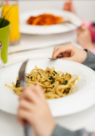 Cropped image of a kid holding fork and knife, having grain free pastaの写真素材