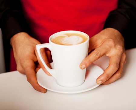 Barista prepares cappuccino in his coffee shop