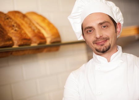 Smiling baker posing for the camera. Freshly baked breads in backgroundの写真素材