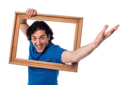 Young man with picture frame filled with excitementの写真素材