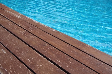 Swimming pool with a wooden flooring beside itの写真素材