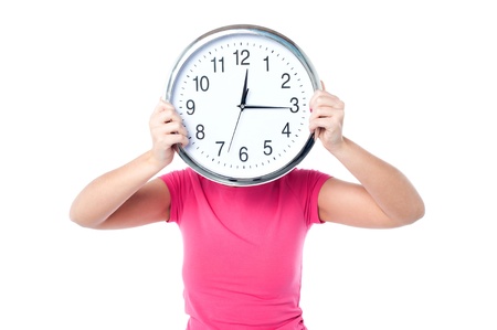 Young girl hiding her face behind wall clock