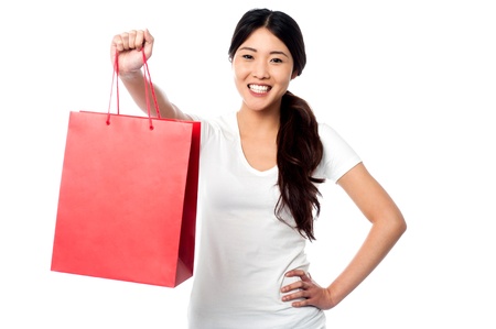 Smiling young female model holding shopping bagの写真素材