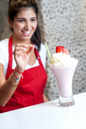 Pretty female chef serving fresh strawberry shakeの写真素材