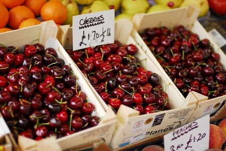 Cherries in focus along with other fruits being sold at marketの写真素材