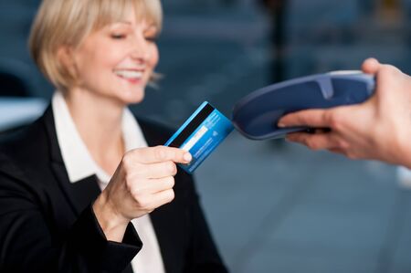 Smiling senior businesswoman swipes her credit card to make the payment.の写真素材