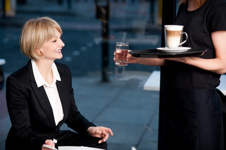 Middle aged businesswoman welcoming her order with smile at a restaurant.の写真素材