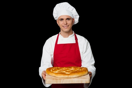 Isolated chef holding bread, black background.の写真素材