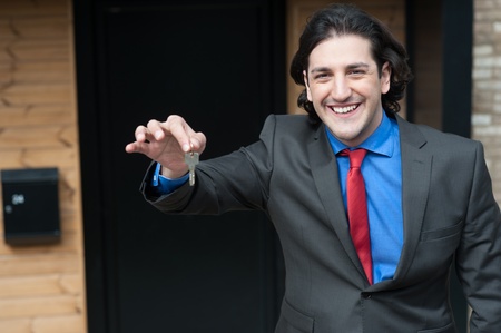 Smiling male professional showing key to the camera の写真素材