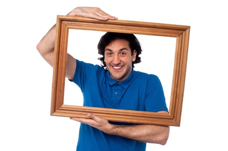 Smiling guy looking through picture frameの写真素材