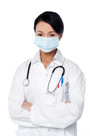 Young female physician covering her face with surgical maskの写真素材