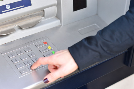 Woman hand entering code into atm machineの写真素材