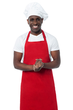 Male chef standing with his hands clasped and smilingの写真素材