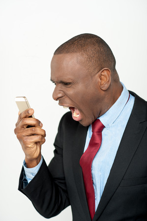 Aggressive businessman yelling into a cellphoneの写真素材