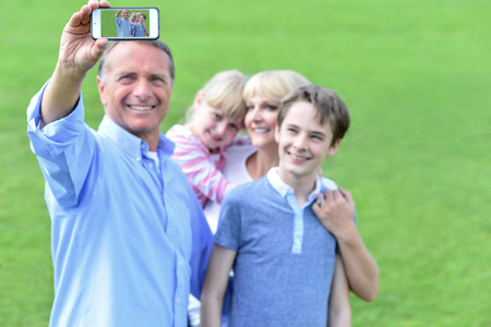 Father taking a family picture, outdoors.の写真素材