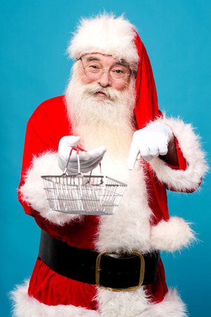Santa claus pointing and showing shopping basketの写真素材
