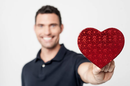 Casual man giving a heart shaped gift to youの写真素材