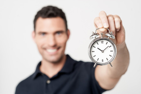 Cheerful young man with alarm clockの写真素材