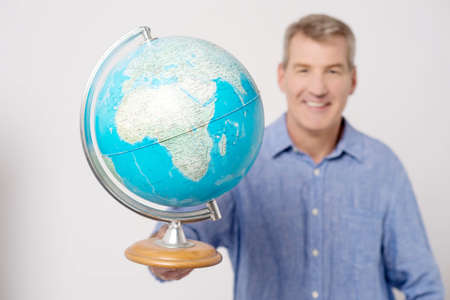 Smiling mature man showing globe to cameraの写真素材