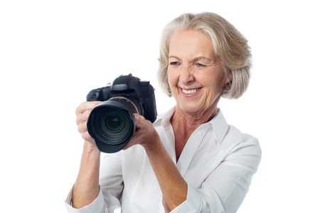 Happy aged woman viewing her photos in DSLR cameraの写真素材