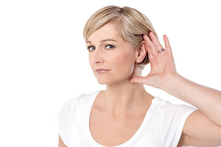 Woman with hand behind her ear and listens carefully
