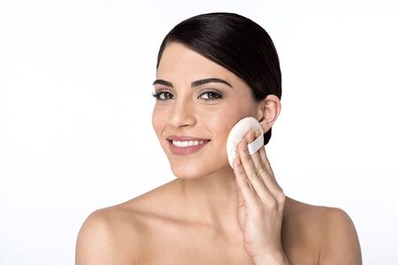 Woman applying cosmetic powder on faceの写真素材