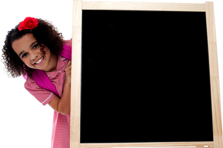 Little girl posing behind the black boardの写真素材