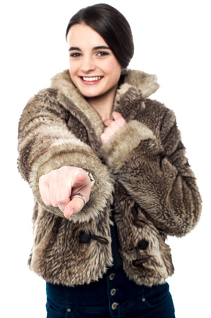 Smiling girl in fur coat, pointing her finger forward.の写真素材
