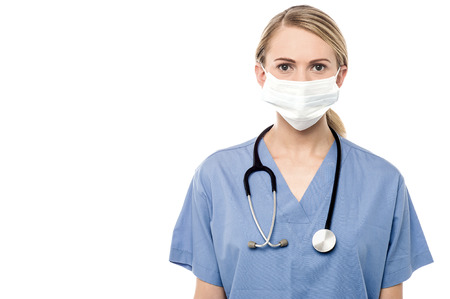 Female surgeon posing with surgical mask over whiteの写真素材
