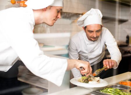 Two male chefs preparing dish at restaurant