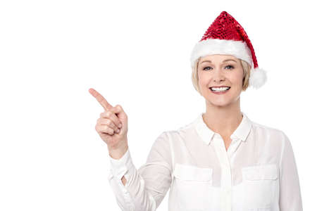Smiling woman pointing away, wearing santa capの写真素材
