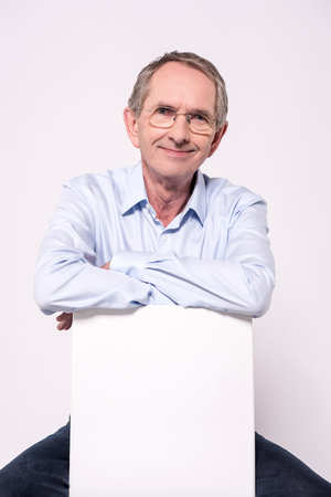 Senior man is holding blank placard on white background.の写真素材