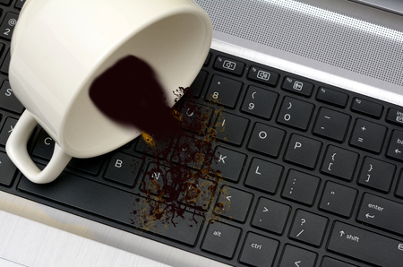 Coffee spilled out of Cup on Laptop Keyboard damage conceptの写真素材