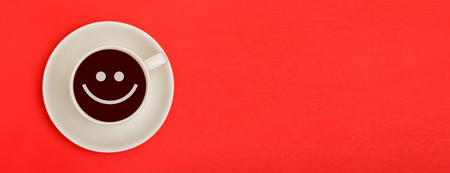 Smile Emoji in coffee cup with banner template on red backgroundの写真素材