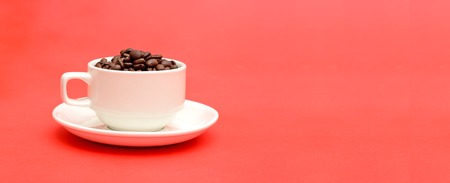 Cup full of roasted coffee beans on red banner templateの写真素材