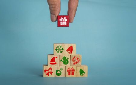 Christmas icons on wooden blocks with man hand, copy space for your text