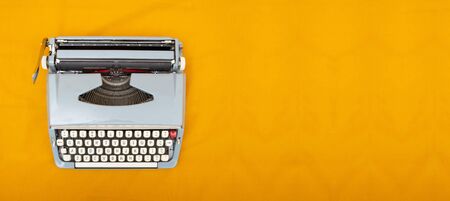 Old vintage style typewriter top view photo on yellow background.