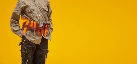 Worker with construction tools on yellow background, labor day conceptの写真素材