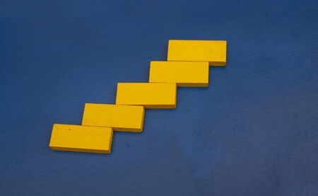 Yellow color wooden cube on blue color background with business success concept