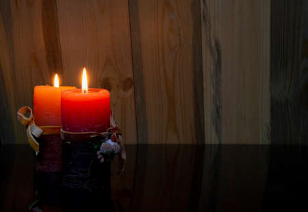 Christmas concept banner with two red candles lighting on wooden backgroundの写真素材