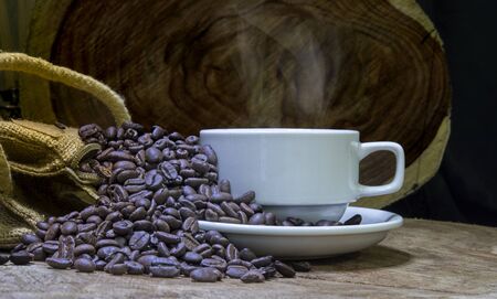 Close up view of coffee bean and cup on wooden background.