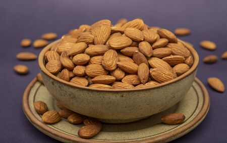 Pile of roasted almonds in a wooden pot close up view.の写真素材