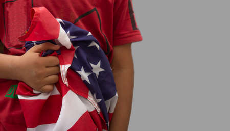Kid holding USA flag in hand close to his body - 4th of July concept