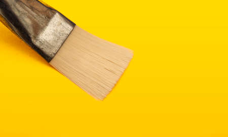 Closeup view of paint brush on yellow cardboard surface