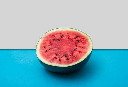 Half cut watermelon on blue table background showing summer concept.